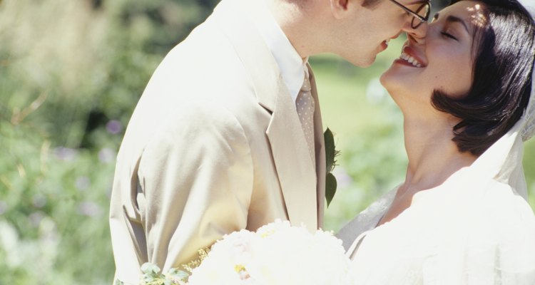 Bride and groom kissing in park, close-up