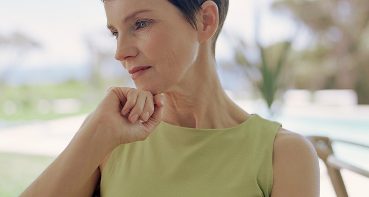 Mature woman resting chin on hand, staring downwards, close-up