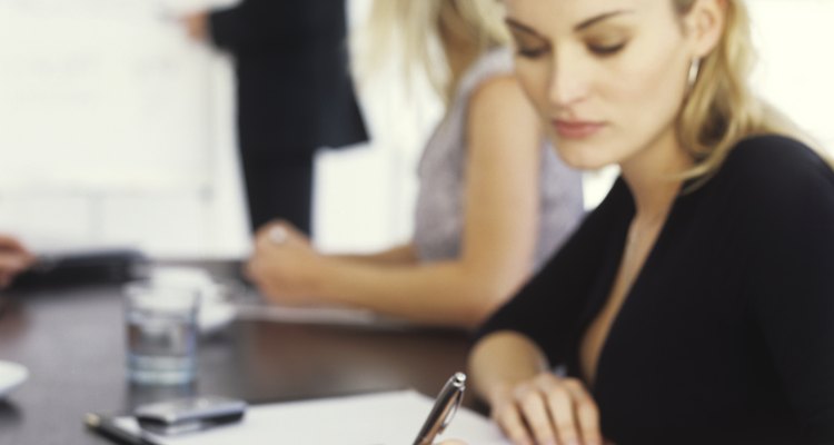 Young businesswoman writing in meeting