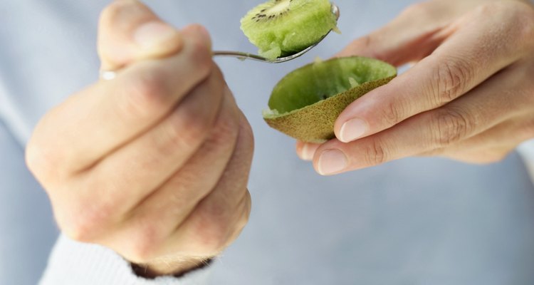 Close-up of a person eating a kiwi with a spoon