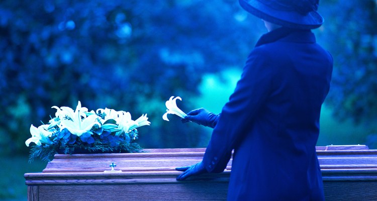 a woman placing a flower on a coffin