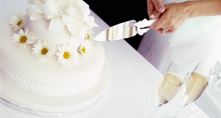 high angle view of a bride and groom cutting the wedding cake