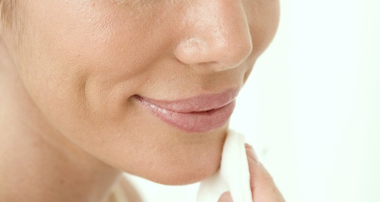 Close-up of a mid adult woman wiping her face with a cotton pad