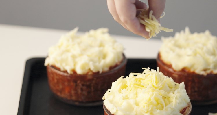 Sprinkling cheese on to uncooked pies, close up