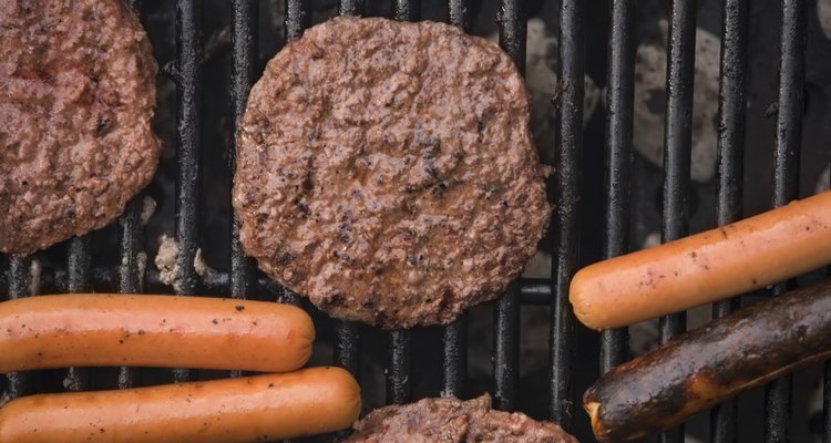 Hamburguesas y perros calientes en una parrilla.