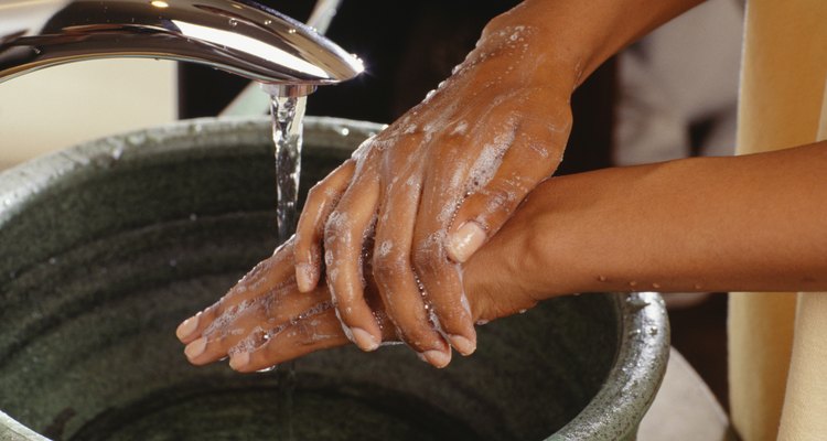 Woman washing hands in bathroom sink, close-up of hands