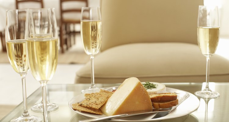 Glasses of wine by plate of cheese and biscuits on coffee table