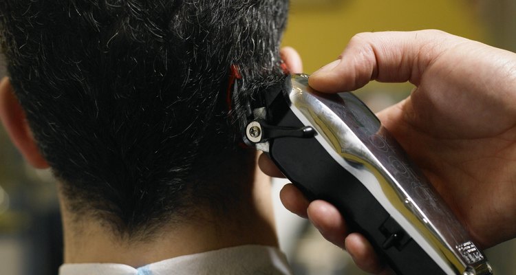 Barber cutting man's hair, close-up of electric razor, rear view