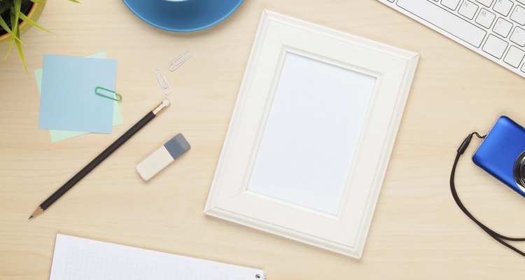 Photo frame on office table with notepad, computer and camera