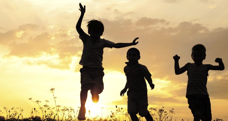 Children running on meadow at sunset