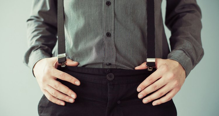 Men's hands holding pants with suspenders