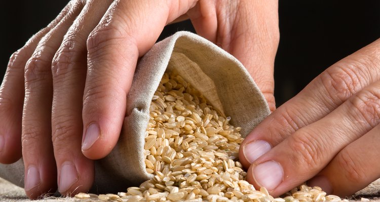 hand with brown rice in linen sack