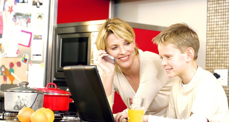 Mother talking on cell phone in kitchen with son