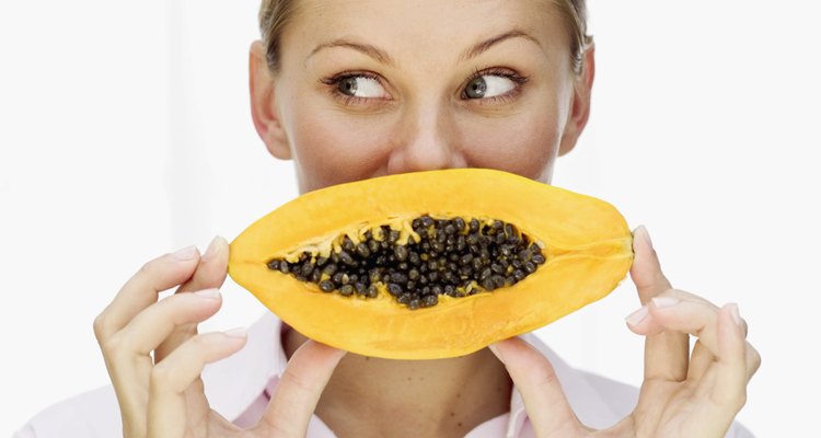 Portrait of a young woman holding a sliced papaya