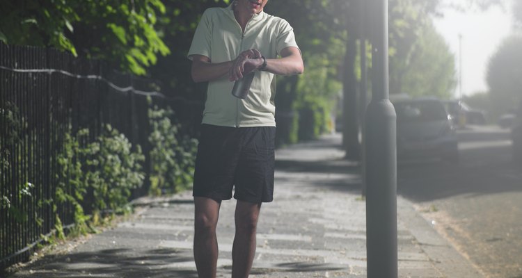 Mid adult man standing at street, looking at watch