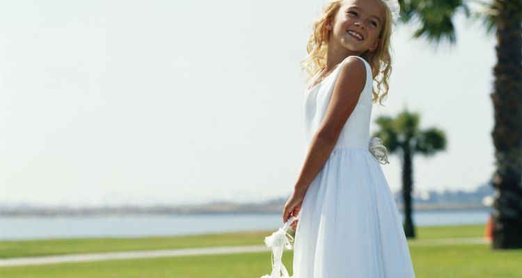 Flower girl (6-9) holding basket, smiling, side view