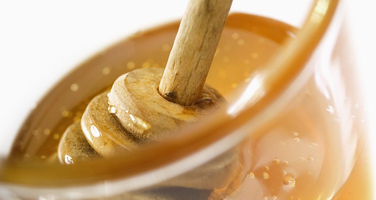 Honey dipper in jar of honey, close-up, tilt