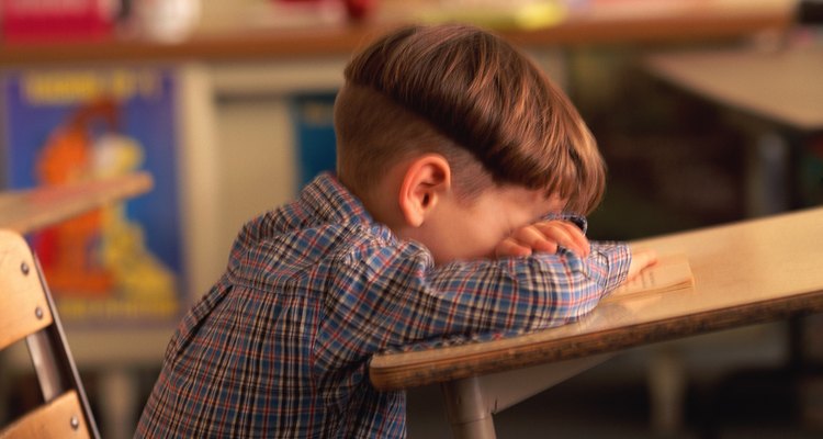 Boy sitting with head down on classroom desk