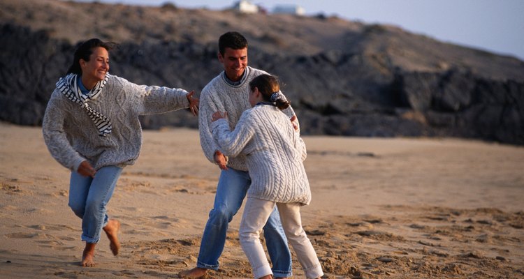 Parents playing with daughter (6-9) on beach