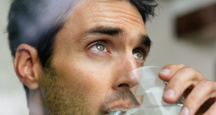 Man drinking glass of water, view through window, close-up