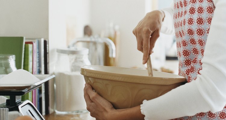 Woman Holding a Bowl and a Wooden Spoon in a Kitchen