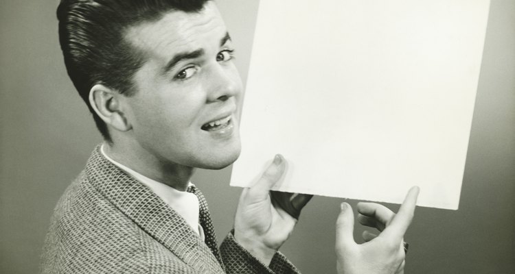 Man holding blank sheet of paper in studio, (B&W), portrait