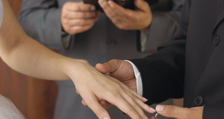 Groom placing ring on bride's finger