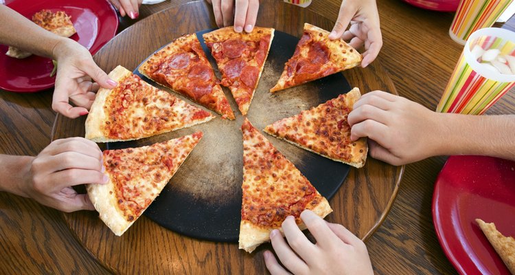 Hands taking slices of pizza