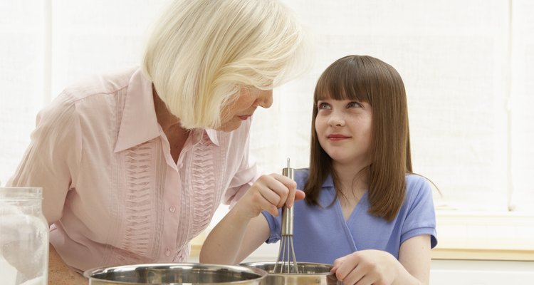 Granddaughter (8-10) and grandmother mixing ingredients in bowl