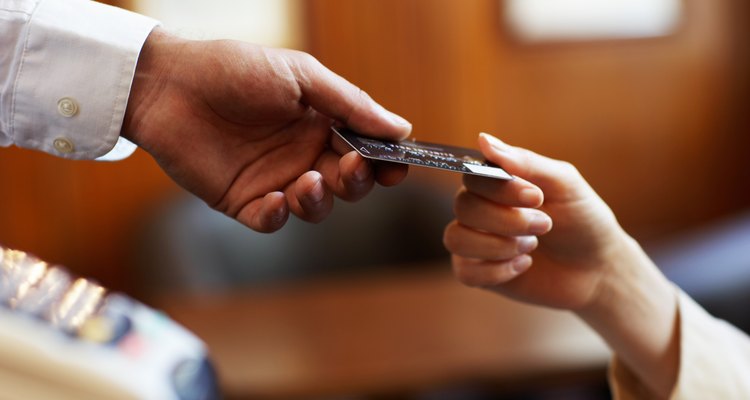 Young woman handing waiter credit card, close-up