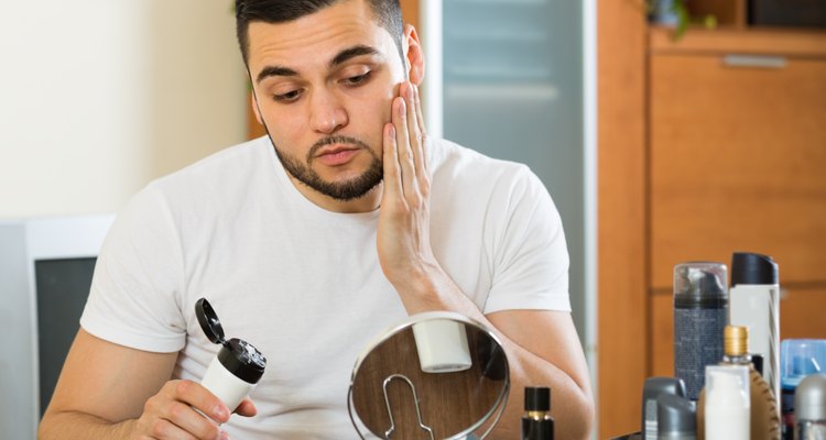 man applying facial cream at home
