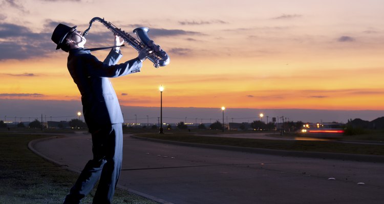 One person playing a saxophone beside Street Lamp