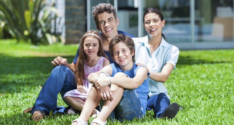 Family with two children sitting in front house