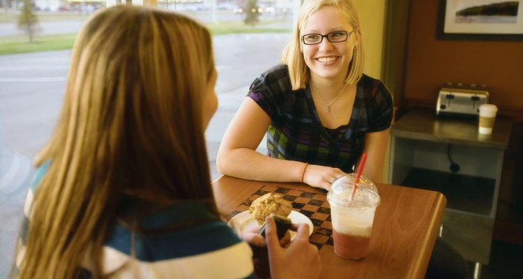 Two Women Talking At A Table In A Cafe