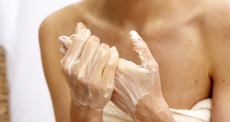 Young woman rubbing creme into hands, mid section, close-up