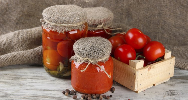 Tasty canned and fresh tomatoes on wooden table