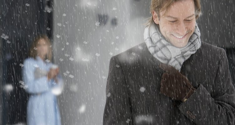 Man leaving house in snow, smiling, woman standing on doorstep