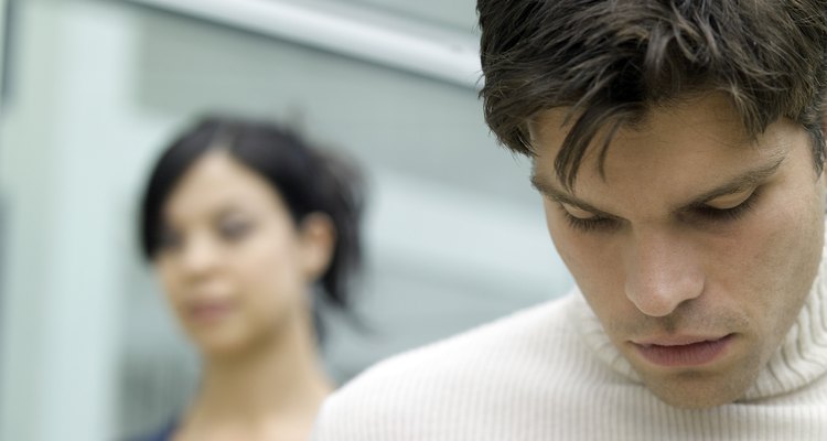 Young man looking down and a young woman behind him