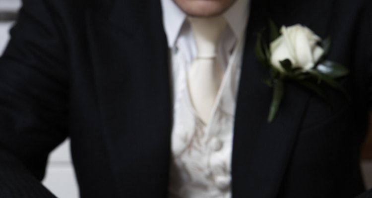 Young groom sitting at table toying with wedding ring, close-up