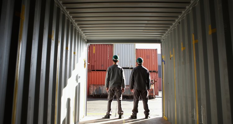 Two men standing in cargo container, looking out, rear view