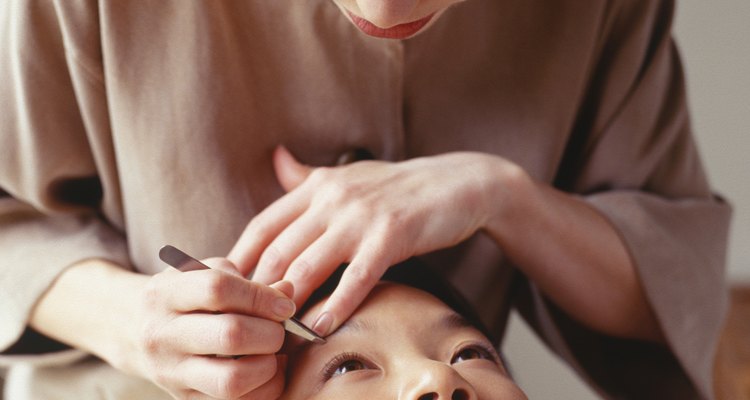 Young woman having eyebrows plucked at beauty parlour