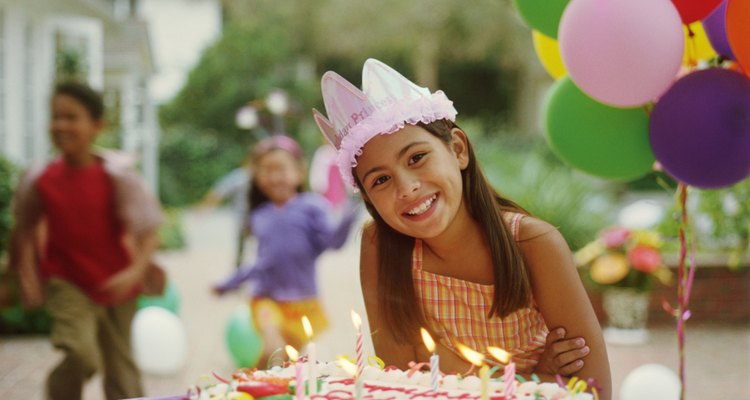 Girl (9-11) at birthday party, leaning over birthday cake, portrait