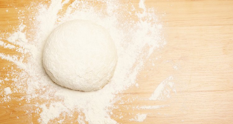Ball of dough with flour on wooden surface