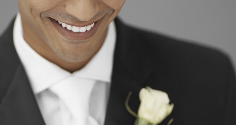 close-up of a groom holding a white rose