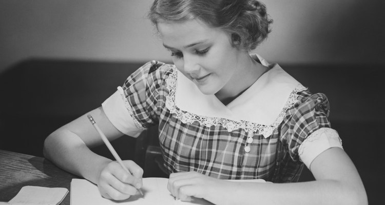 Young girl (12-13) at table doing schoolwork, (B&W)