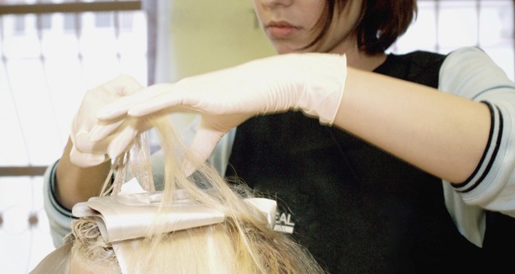 Close-up of a female hairdresser dyeing a mid adult woman's hair