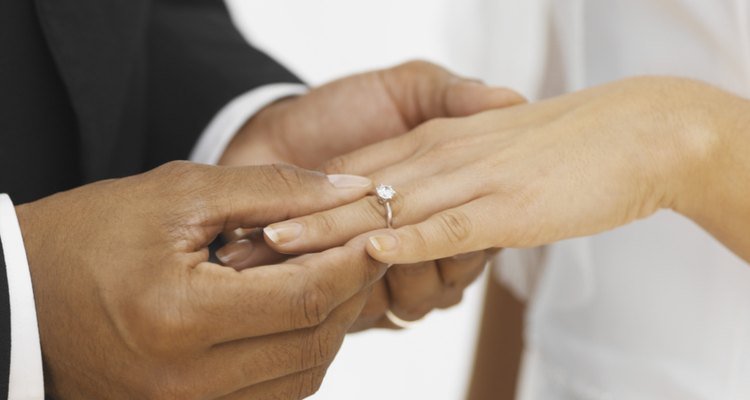 close-up of a groom putting a ring on his bride's finger