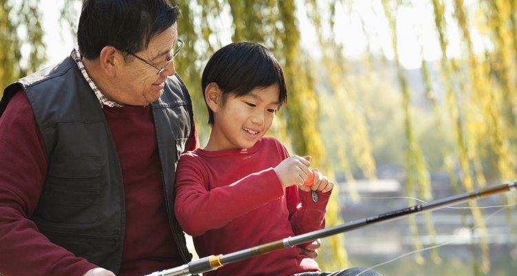 Grandfather and grandson putting lure on fishing line