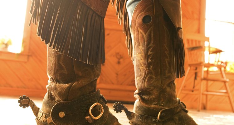 Boots and spurs with chaps on legs of cowboy