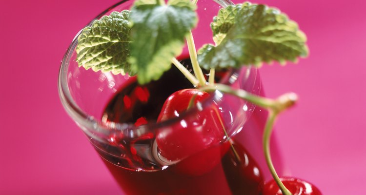 Glass of juice with cherry and mint leaf, close-up